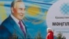 Kazakhstan -- A woman walks past a poster depicting Kazakh President Nursultan Nazarbaev in Almaty, February 16, 2015