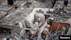 Palestinians check the damage at the site of Israeli strikes on houses in Khan Younis